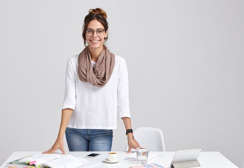 A young woman standing at a desk with a laptop, engaged in MCCQE1 exam preparation with Ace QBank.