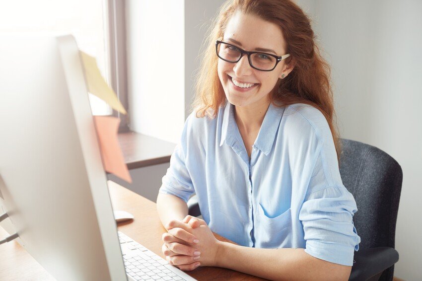 A woman wearing glasses is sitting at a desk in front of a computer, studying for her MCCQE1.