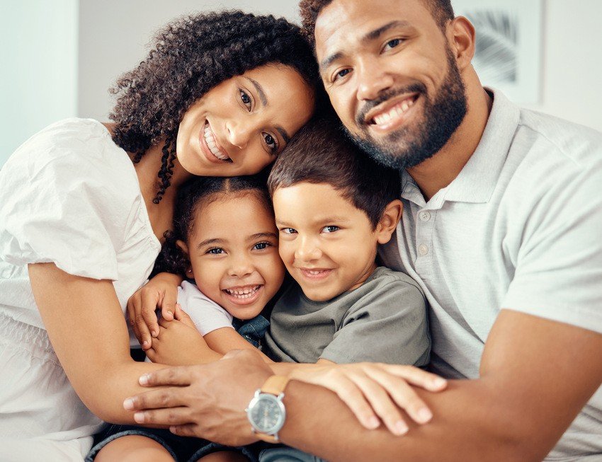 A family is smiling while sitting on the couch, father is preparing for his MCCQE1 exam.