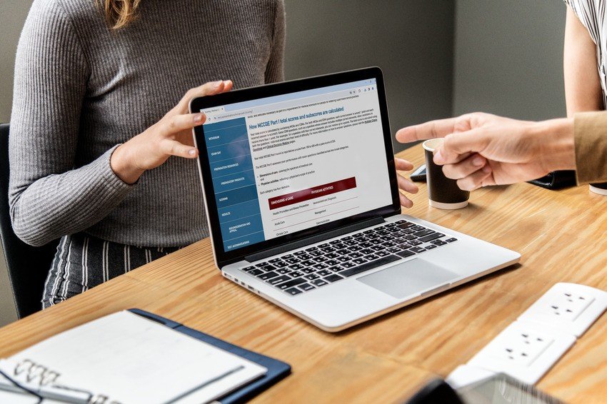 Two people pointing at a laptop with MCC objectives on it, preparing for the MCCQE1 exam using Ace QBank.