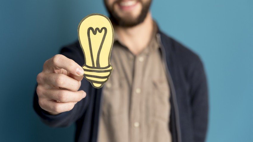 A man is holding up a light bulb as sharing tips for the MCCQE1 exam preparation.