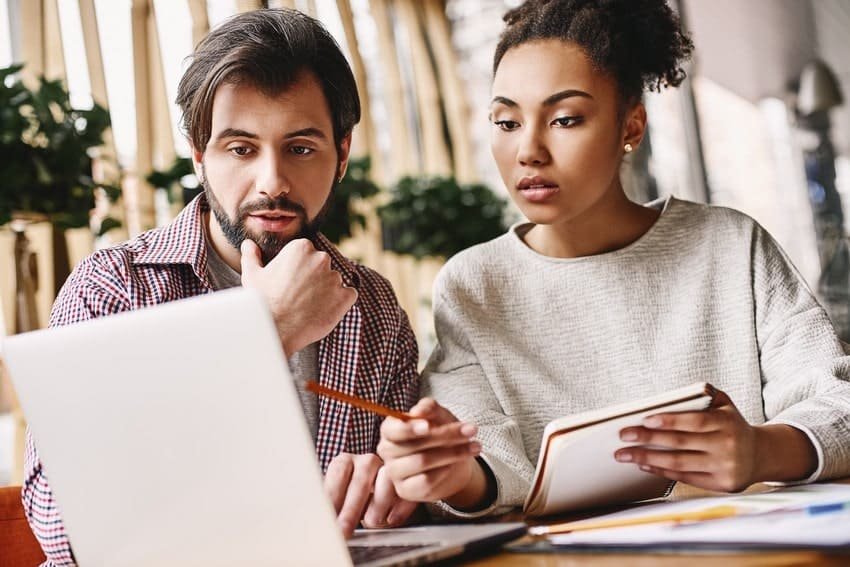 Two people sitting at a table looking at a laptop while preparing for the MCCQE1 exam using a question bank.