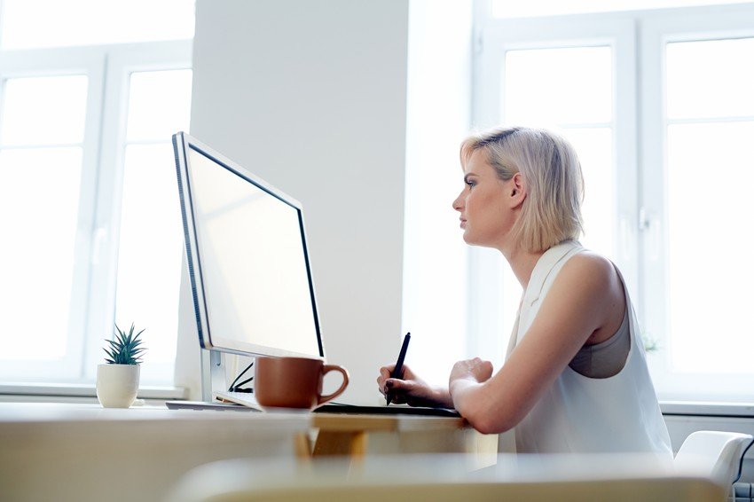 A woman sits at a desk, glancing at a computer screen while using Ace QBank for MCCQE Part 1.