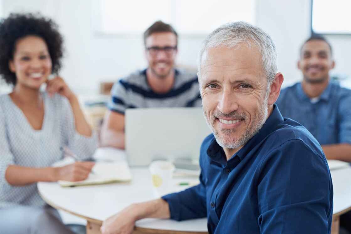 Group of professionals smiling in a collaborative office setting, focusing on MCCQE1 exam preparation.