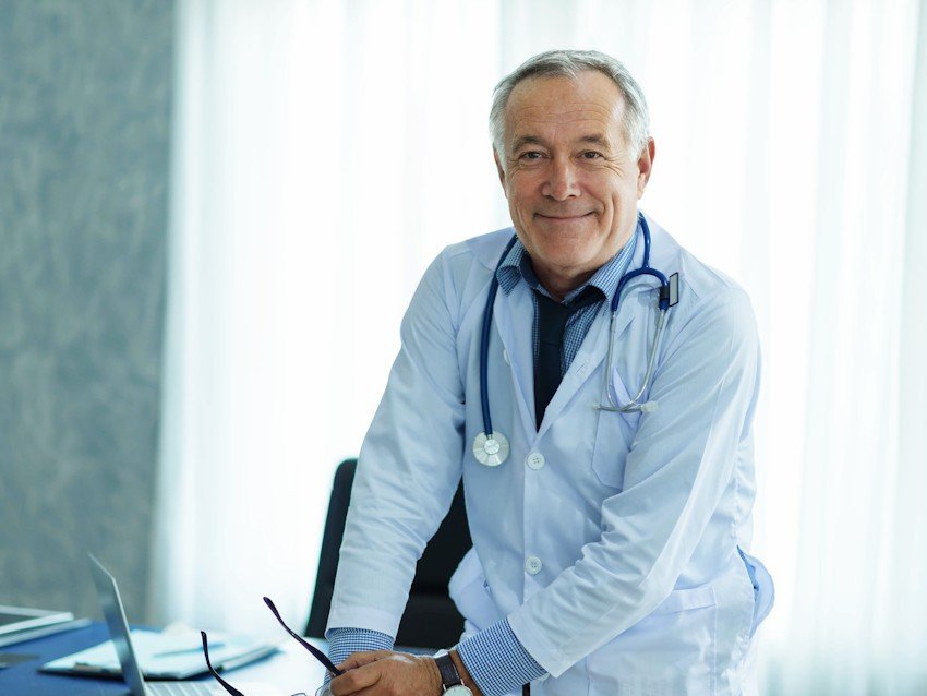 A male doctor standing in front of a desk, talking about the MCCQE1 exam preparation using Ace QBank.