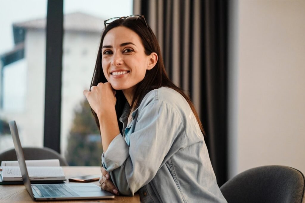 Medical Student smiling at the camera while sitting at a desk with a laptop, creating MCCQE1 study plan