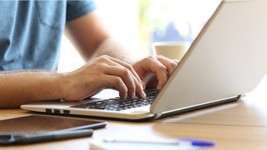 Medical student typing on a laptop at a wooden desk with a coffee cup and stationery items, searching for Ace QBank website.