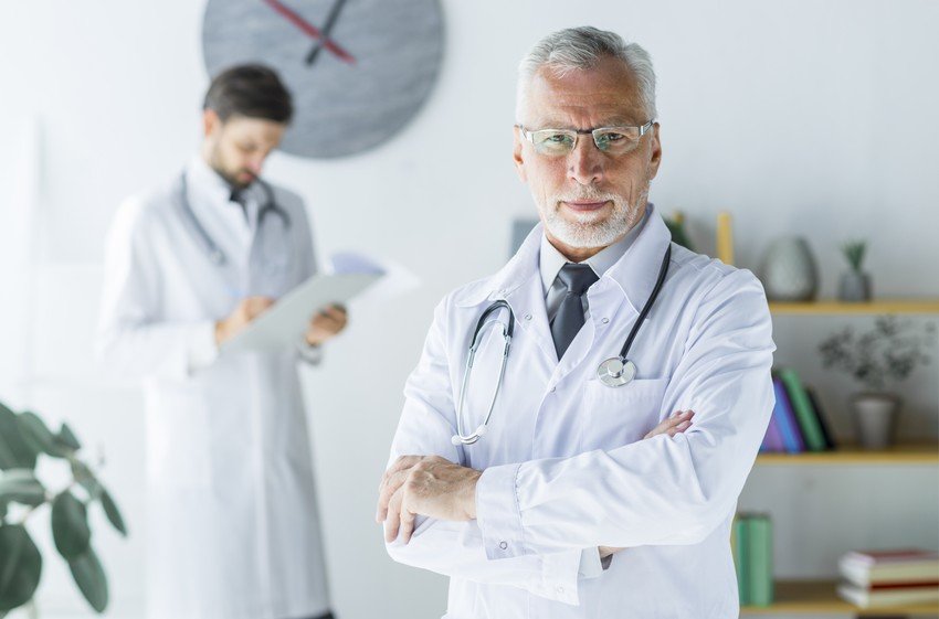 Senior doctor with another male doctor in the background, after discussing MCCQE Part 1 Prep Hidden Costs & Risks.