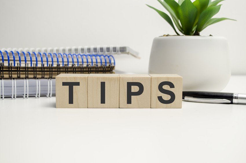 Wooden blocks spelling "TIPS" are displayed on a desk with spiral notebooks, a pen, and a potted plant in the background, offering calming strategies for MCCQE1 exam anxiety.