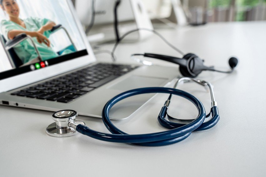 A stethoscope and a headset rest on a table beside an open laptop, showcasing telemedicine in action with a person in a video call for blog title MCC Objective Not for MCCQE1 But Telemedicine that helps to prepare with Ace QBank for MCCQE1.
