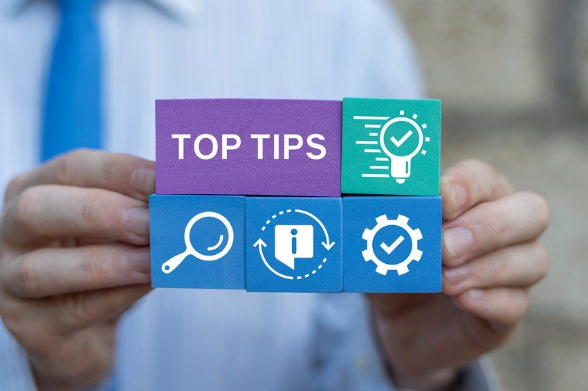 A person holds blocks labeled "Top Tips," featuring icons like a magnifying glass, information symbol, clock, and gear. These elements align perfectly with tools like Ace QBank for mastering MCCQE1 through insightful tips and MCCQE Part 1 Sample Questions.