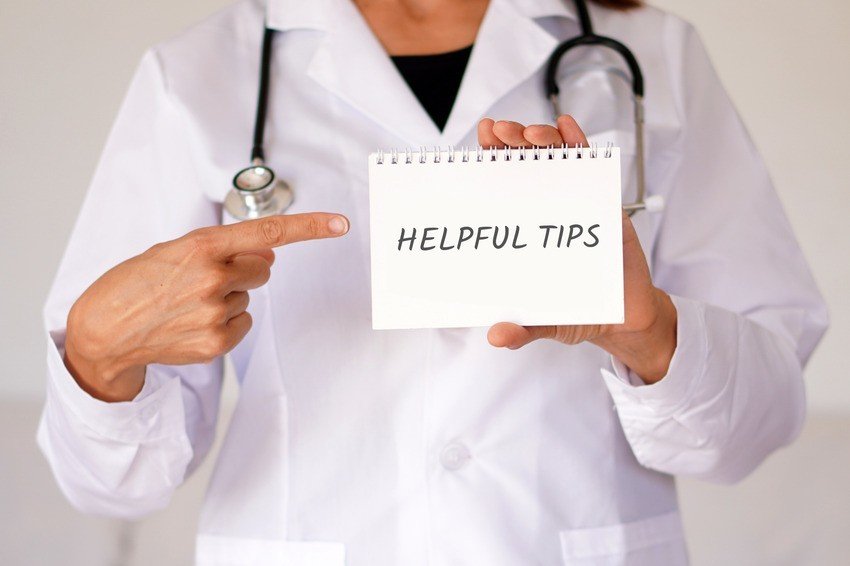 A doctor in a white coat points to a notepad with "Helpful Tips" written on it, offering insights for MCCQE1 exam preparation.