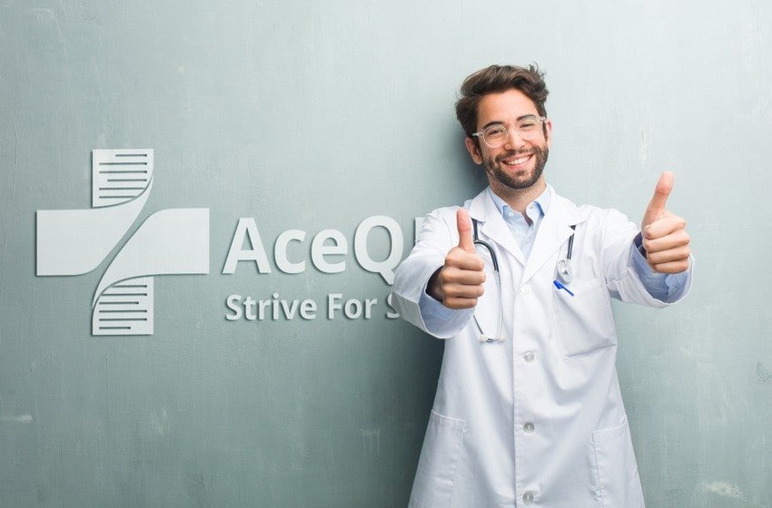 A male doctor in a white coat stands in front of a wall with the "Ace QBank" logo, smiling and giving two thumbs up, confident in his MCCQE1 Exam Prep with Ace QBank.