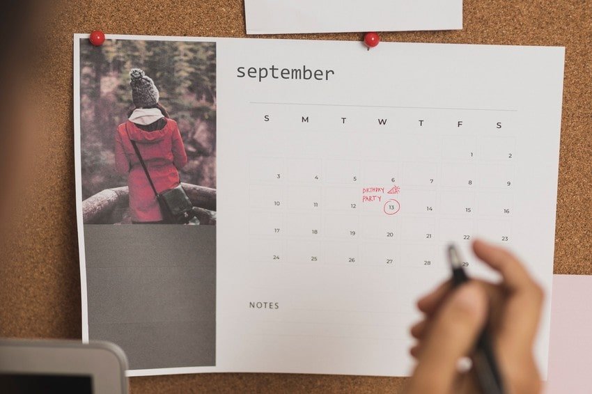 A hand holding a pen points towards a wall calendar for September; the 14th is marked with "MCCQE1 exam," and a reminder for MCCQE1 exam preparation with Ace QBank.