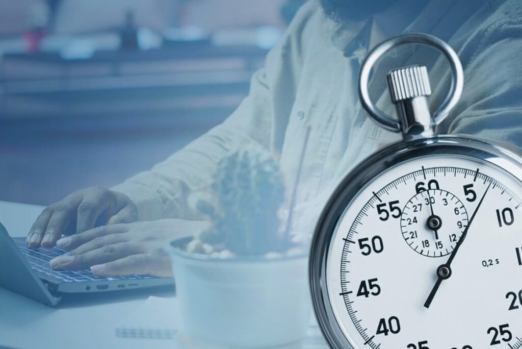 A person types on a laptop at a desk with a small potted plant, while a large stopwatch shows roughly 22 seconds. capturing the focus and efficiency needed for MCCQE1 exam preparation with Ace QBank.