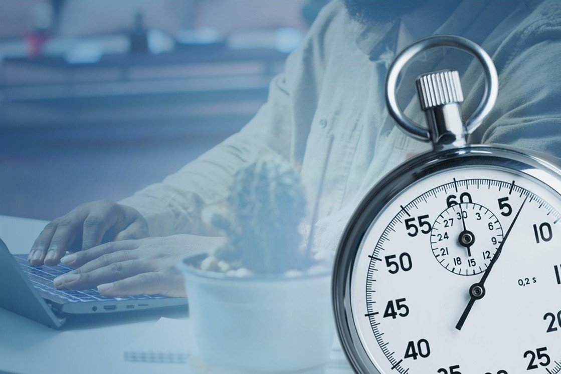 A person types on a laptop at a desk with a small potted plant, while a large stopwatch shows roughly 22 seconds. capturing the focus and efficiency needed for MCCQE1 exam preparation with Ace QBank.