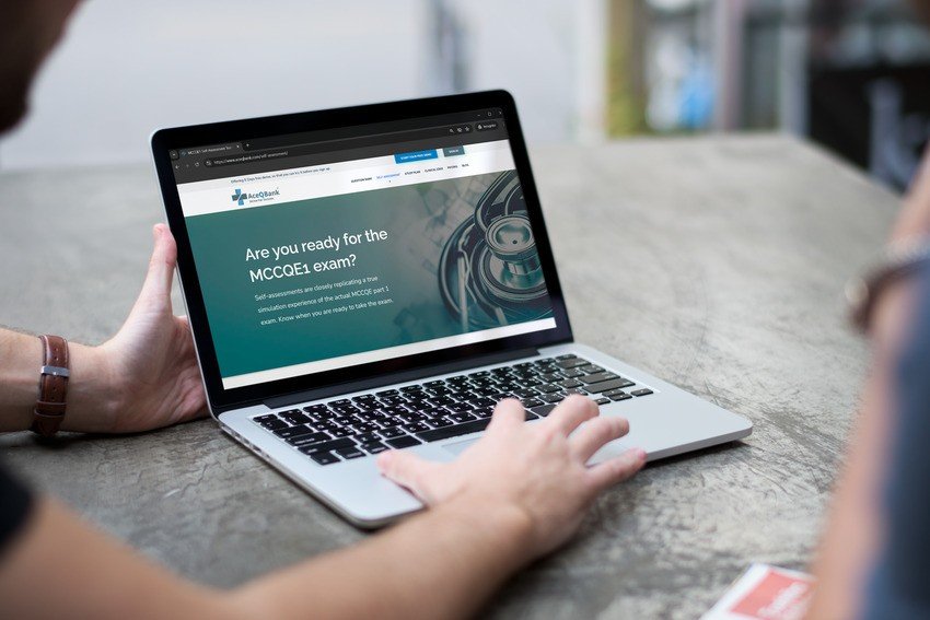 Person using a laptop displaying the Ace QBank website, preparing users for the MCCQE1 exam, with informative text and a stethoscope graphic visible on the screen.