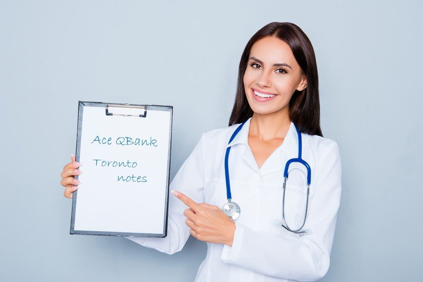 A woman in a white lab coat with a stethoscope smiles and points at a clipboard displaying the text "Ace QBank Toronto notes," perfect for effective MCCQE1 exam prep.